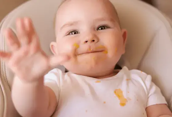 Bebé feliz con su cara llena de comida