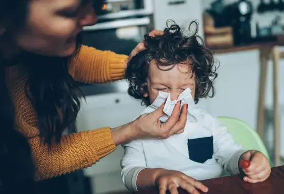 Mama limpiando con pañuelo la nariz de su hijo