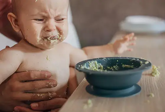 Mama tratando de alimentar a niño llorando