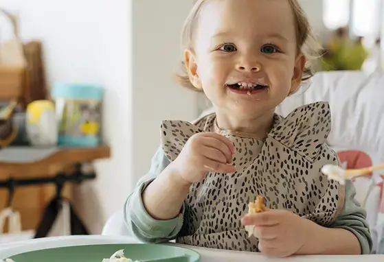 Bebe alegre comiendo con su mama