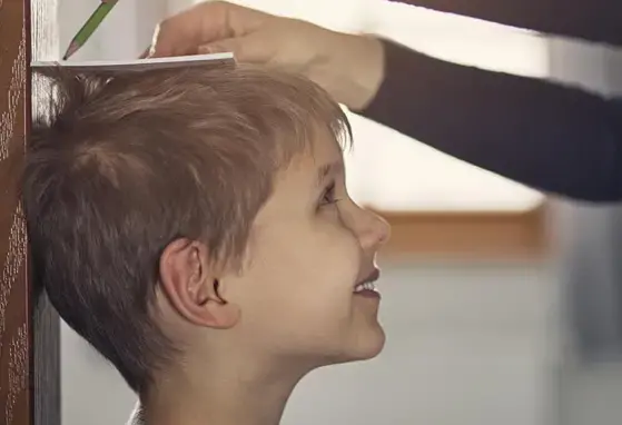 Adulto tomando nota de la altura de un niño