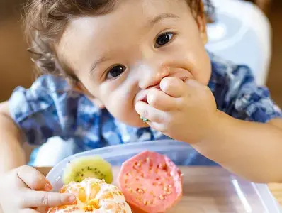 Bebe comiendo alimentos con la mano