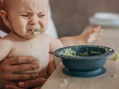 Mama tratando de alimentar a niño llorando